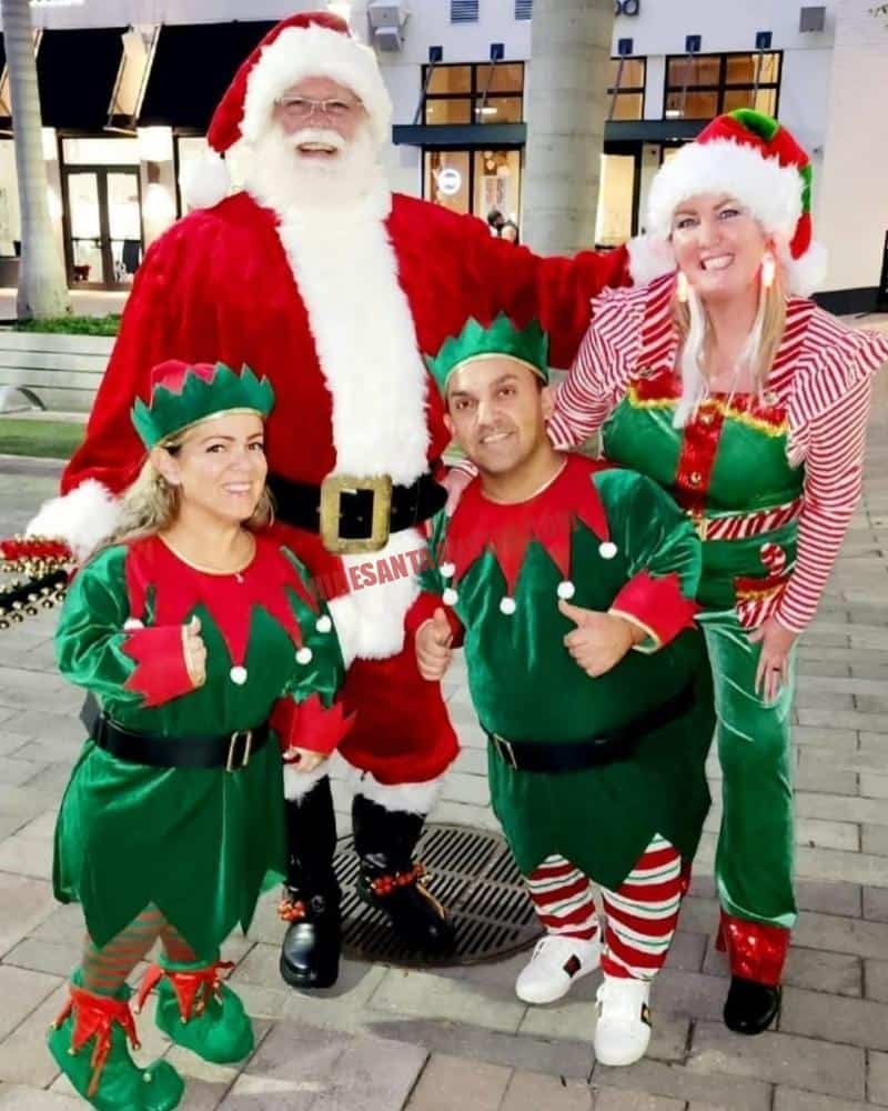 Hire Santa Georgetown: Santa in a red suit with three elves in green costumes.